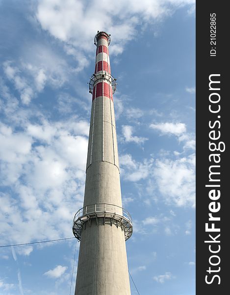 Clean factory chimney on blue sky with white clouds