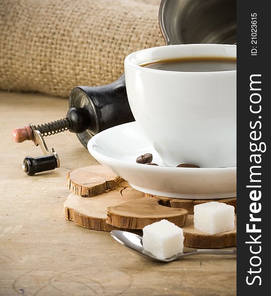 Cup of coffee and grinder with roasted beans