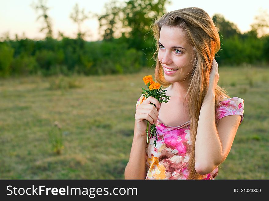 Portrait of a happy young girl smiling and holding orange flowers in her hands outdoor in summertime. Portrait of a happy young girl smiling and holding orange flowers in her hands outdoor in summertime