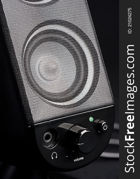Detail of black active speaker with volume control and headset connector.