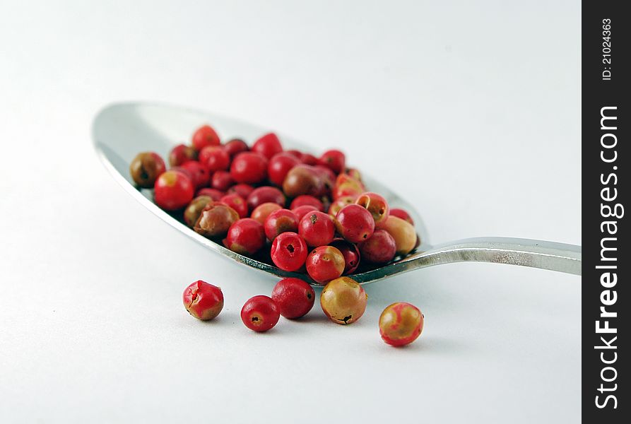 Whole red peppercorns on a spoon