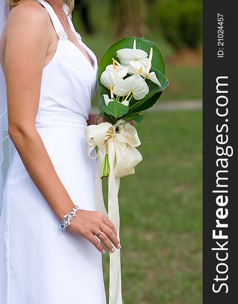 A photograph of a caucasion bride holding a bouquet without showing her head. A photograph of a caucasion bride holding a bouquet without showing her head