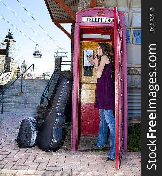 Young woman calling from a phone booth at a ski resort. Young woman calling from a phone booth at a ski resort