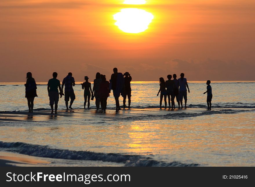 A view of a sunset in the Maldives with silouettes of people in the distance. A view of a sunset in the Maldives with silouettes of people in the distance.