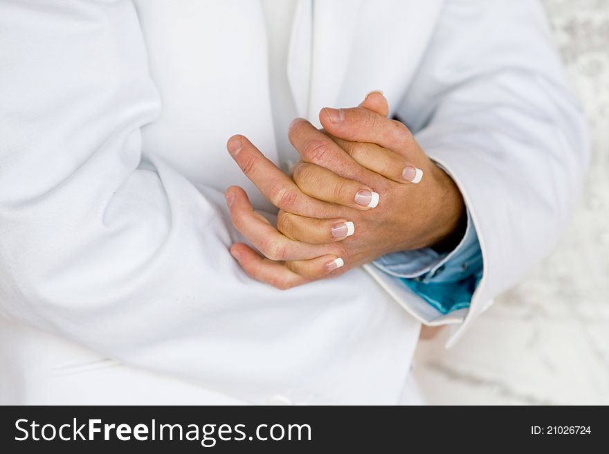 A horizontal photo of a caucasian bride and groom holding hands during a wedding reception