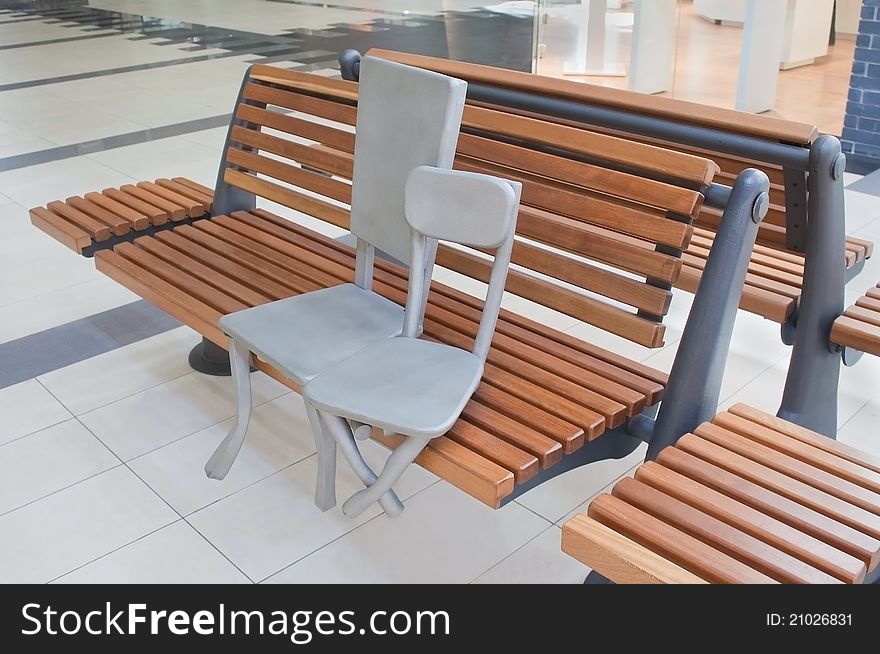 Sculpture of two chairs sitting on a bench in shopping mall. Sculpture of two chairs sitting on a bench in shopping mall