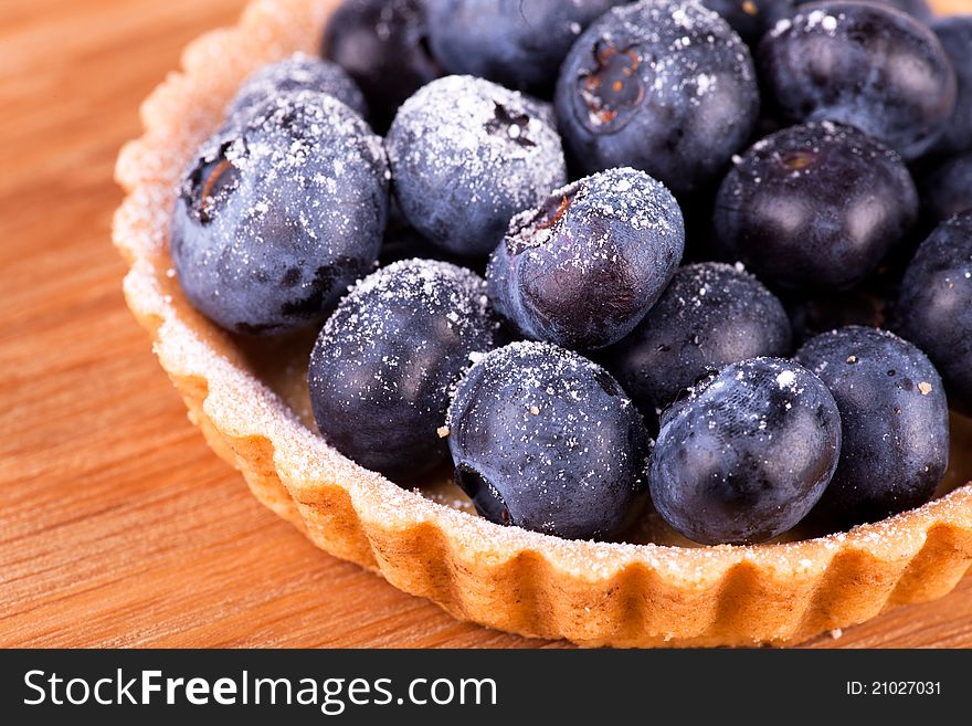 Macro picture of blueberries tart on the wooden board