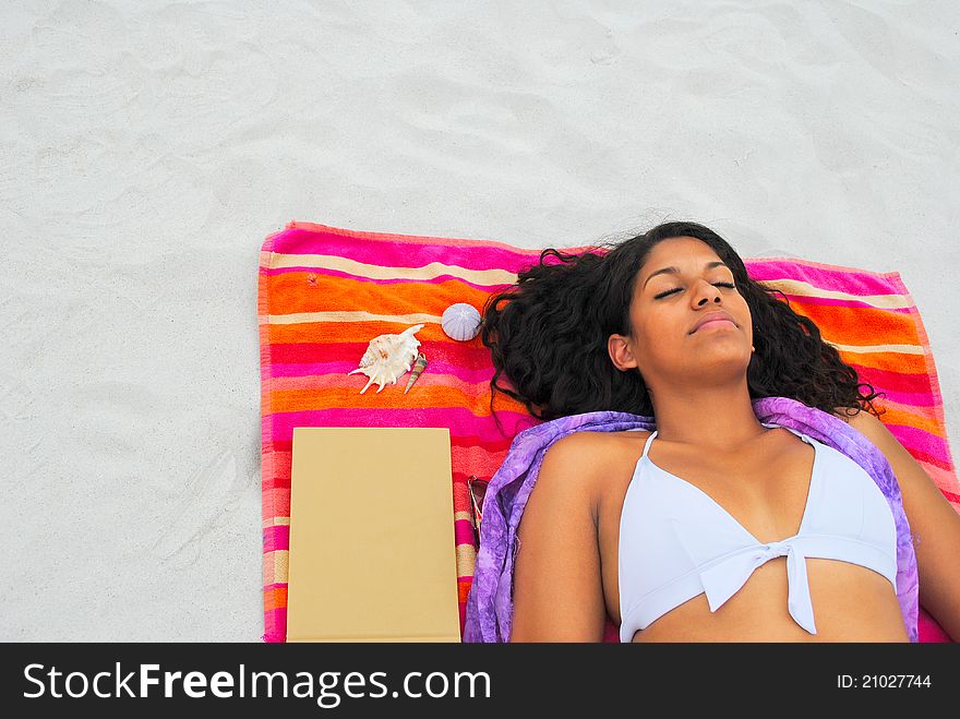 Pretty woman relaxing at the beach on a colorful towel