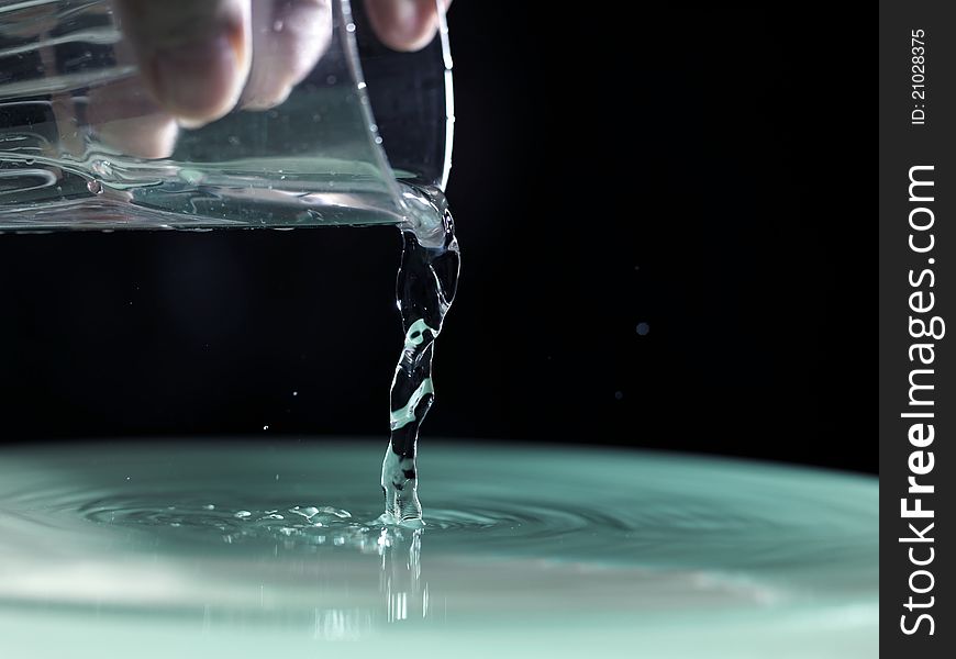 Water pouring into glass on black background