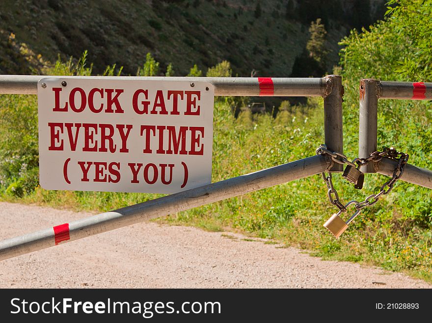 Image of a gate with a lock and a sign yes you. Image of a gate with a lock and a sign yes you