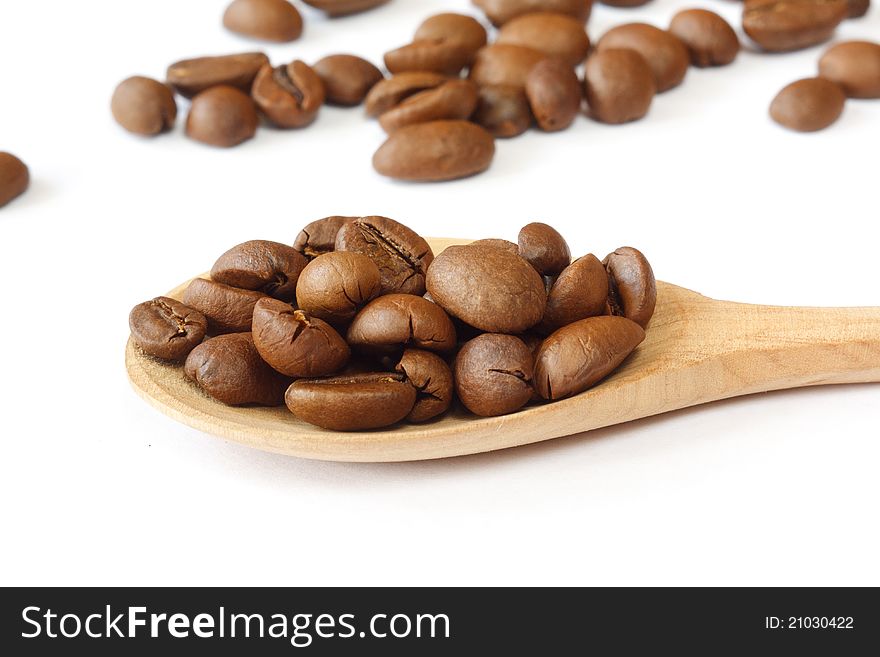 Coffee grains in a wooden spoon on a white background