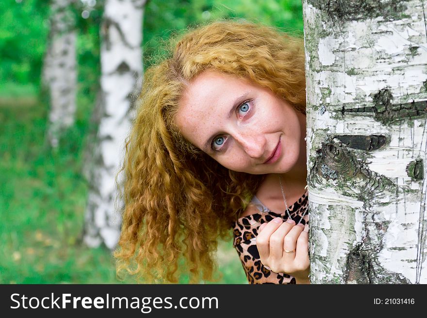 Beautiful girl looking out behind the tree outdoor