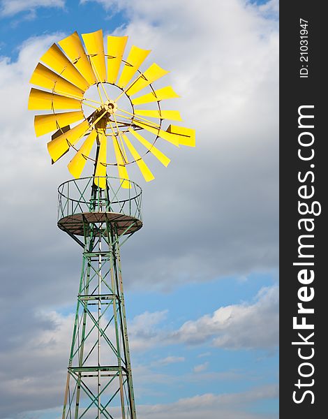 Yellow windmill and blue sky with clouds behind it. Yellow windmill and blue sky with clouds behind it