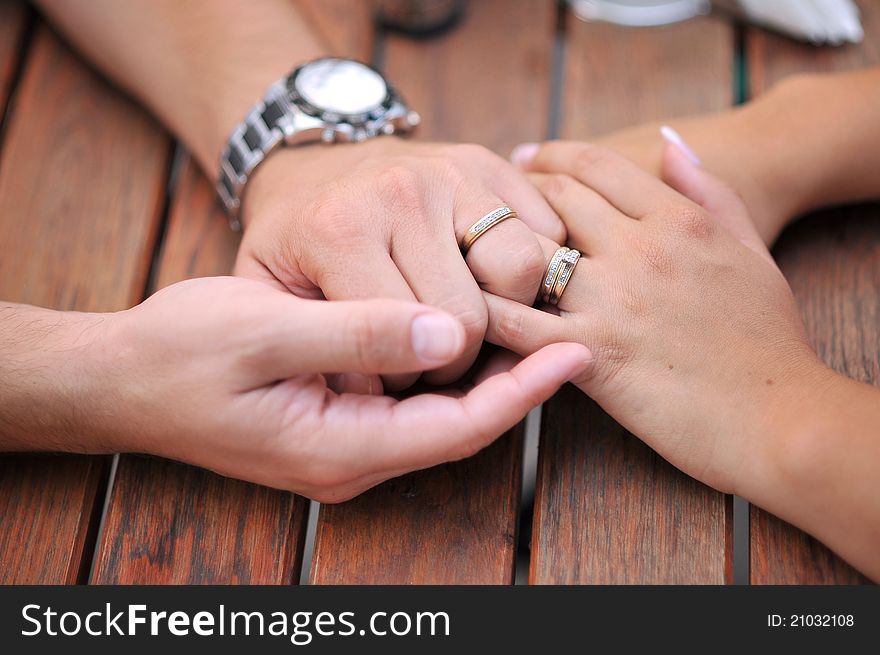 A married couple holding their hands on a table. A married couple holding their hands on a table