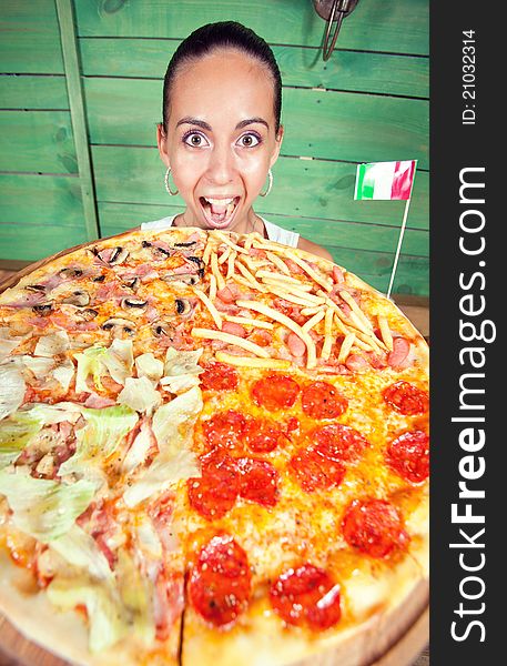 Portrait of young woman with pizza at kitchen