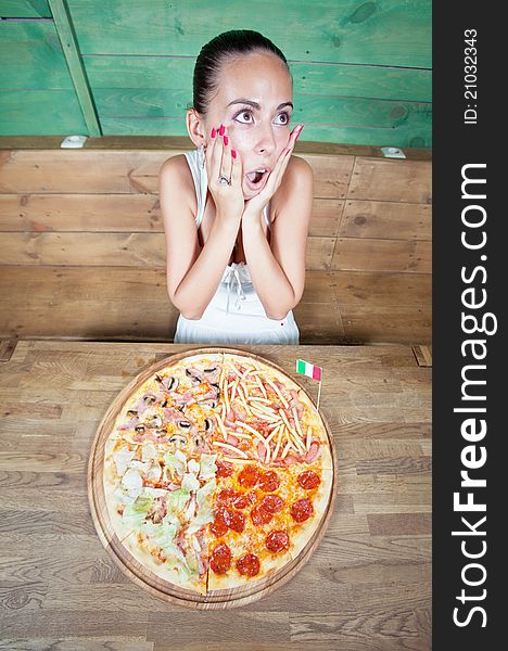 Portrait of young woman with pizza at kitchen