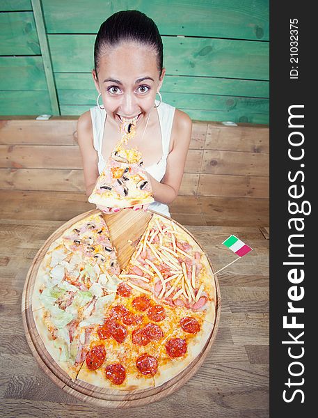 Portrait of young woman with pizza at kitchen