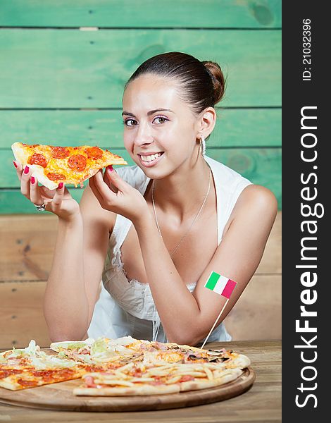 Portrait of young woman with pizza at kitchen