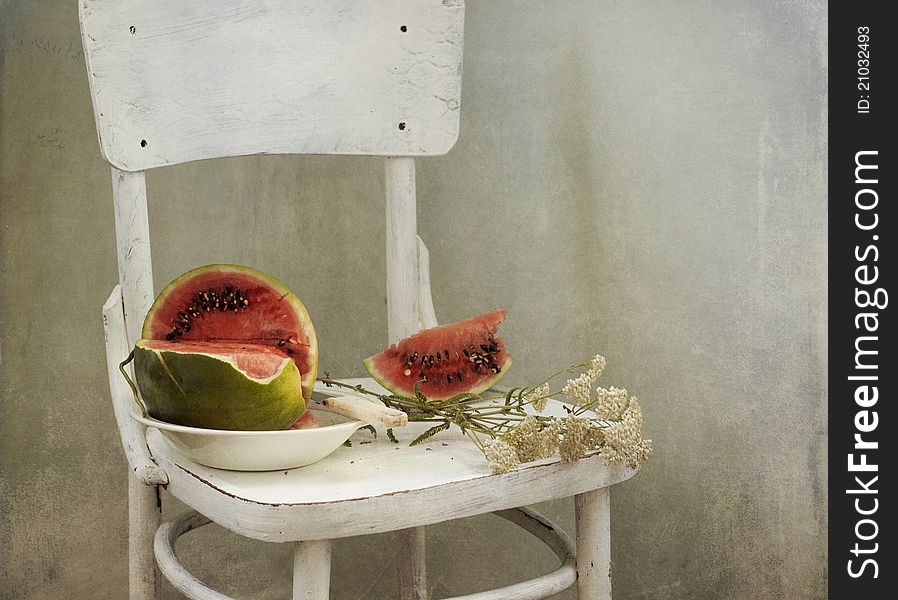 Water-melon and flowers on a white chair. Water-melon and flowers on a white chair