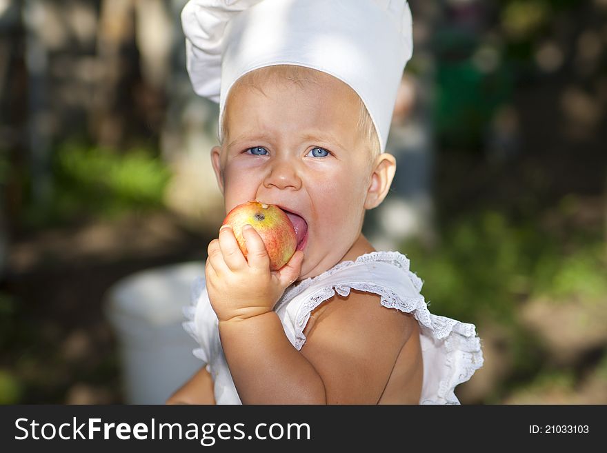 Little baby in the cook hat with an apple. Little baby in the cook hat with an apple.