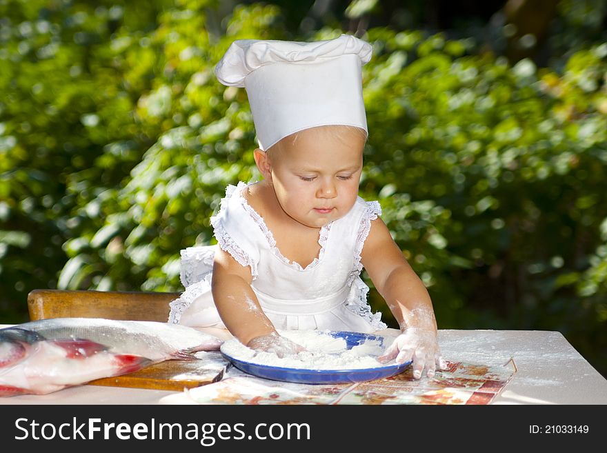 Cute little baby preparing fish, and hands in the flour. Cute little baby preparing fish, and hands in the flour.