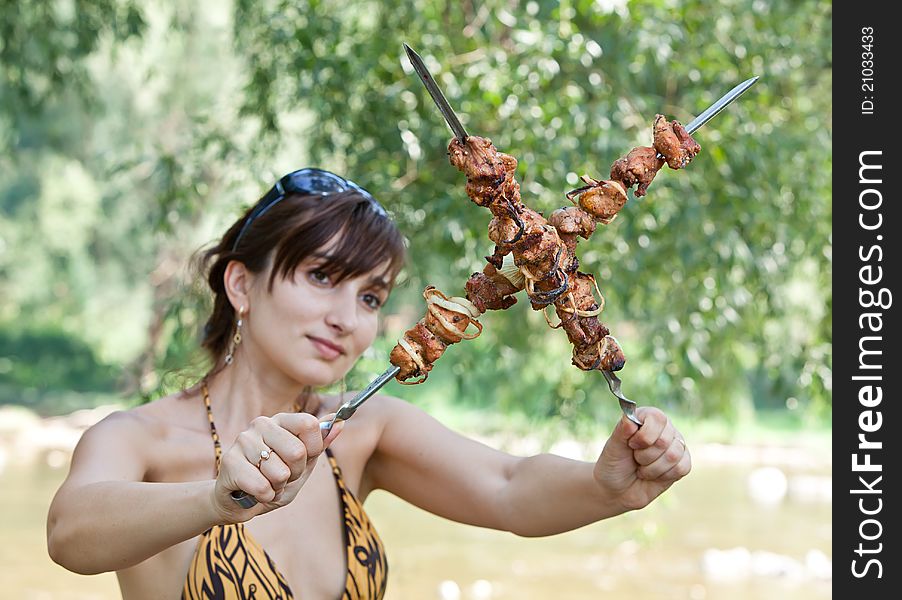 Young woman on a picnic with grilled meaton a picnic with grilled meat. Young woman on a picnic with grilled meaton a picnic with grilled meat