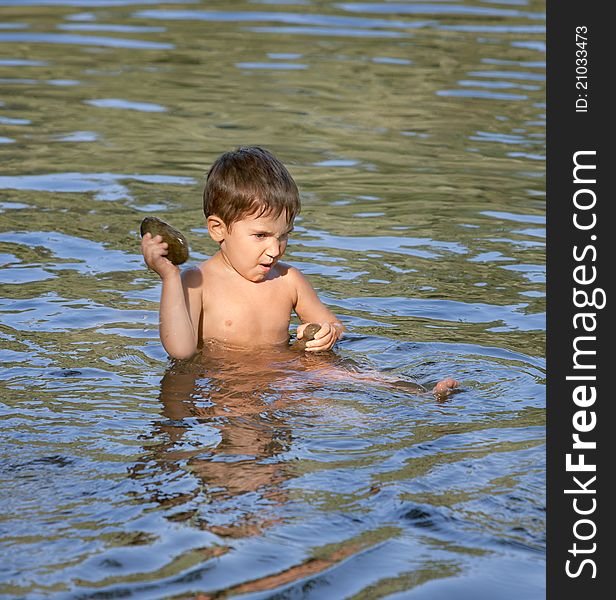 Boy sits in the river and played with a stone. Boy sits in the river and played with a stone
