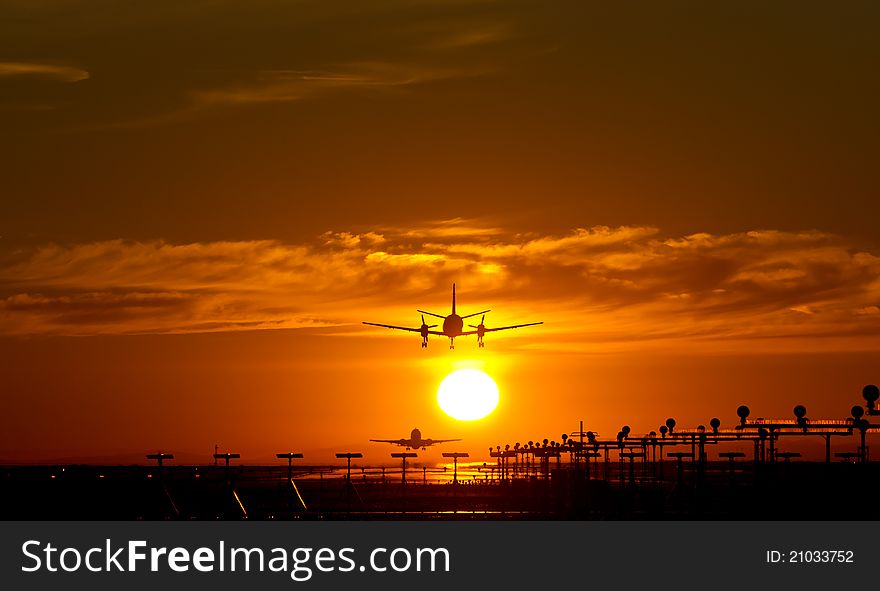Aircraft landing at dusk, with orange sun and clouds. Aircraft landing at dusk, with orange sun and clouds