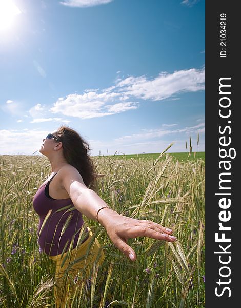 Pregnant woman on green grass field under blue sky in summer