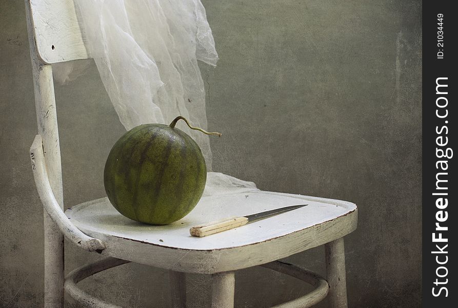 Water-melon and knife on a white chair
