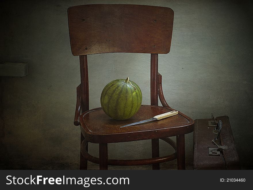 Water-melon and knife on a brown chair