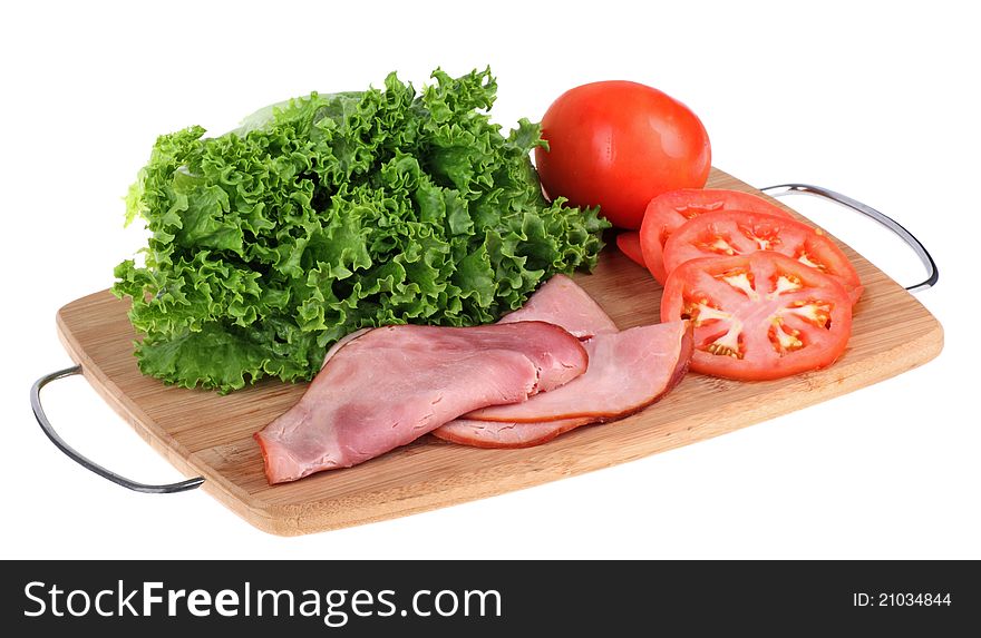 Ham, lettuce and tomato on a cutting board isolated on white. Ham, lettuce and tomato on a cutting board isolated on white