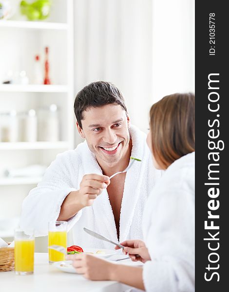 Attractive male feeds the female in the kitchen. Attractive male feeds the female in the kitchen