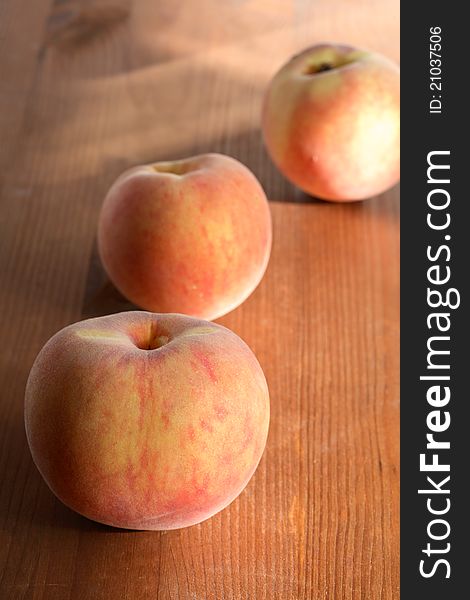 Three freshness peach fruits lying on wooden surface. Three freshness peach fruits lying on wooden surface