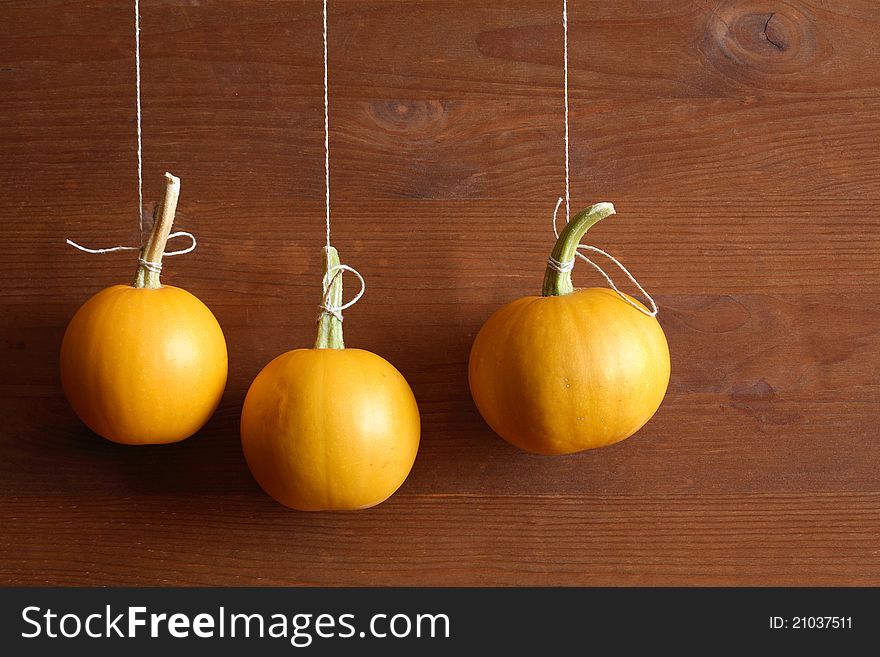 Halloween symbol. Three pumpkins hanging with rope against wooden background. Halloween symbol. Three pumpkins hanging with rope against wooden background