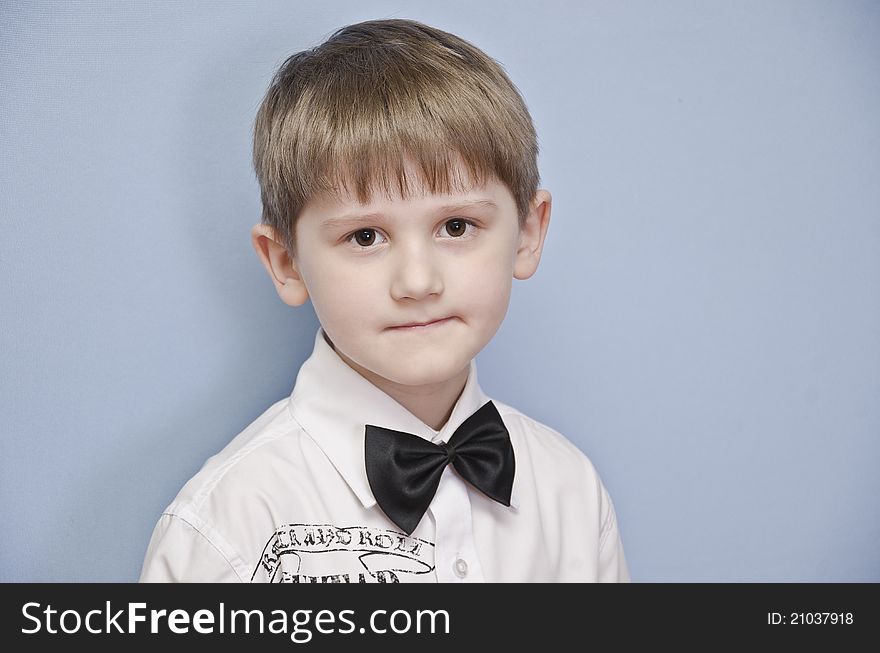 The boy in a white shirt with a tie-butterfly on a monophonic background. He is almost ready to take part in concert. The boy in a white shirt with a tie-butterfly on a monophonic background. He is almost ready to take part in concert.