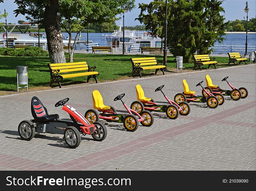 A row of kid's pedal cars parked. A row of kid's pedal cars parked