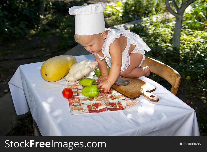 Little cook climbed on a table with vegetables. Little cook climbed on a table with vegetables.