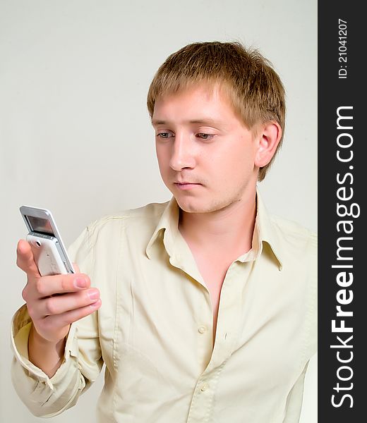The Young Man Looks At A Mobile Phone