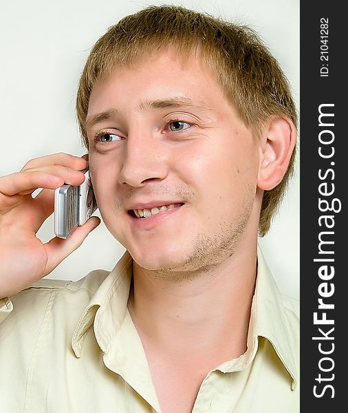 The cheerful young man speaks by phone in studio.