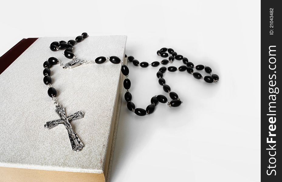 A rosary resting on the bible with white clean background. A rosary resting on the bible with white clean background