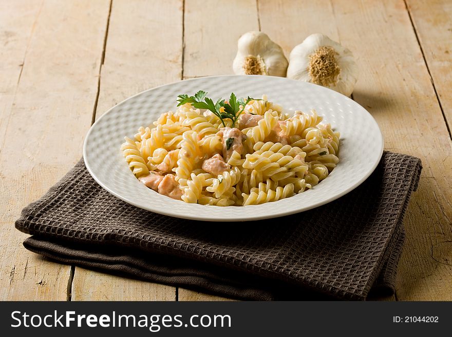 Photo of delicious pasta with salmon and cream on wooden background