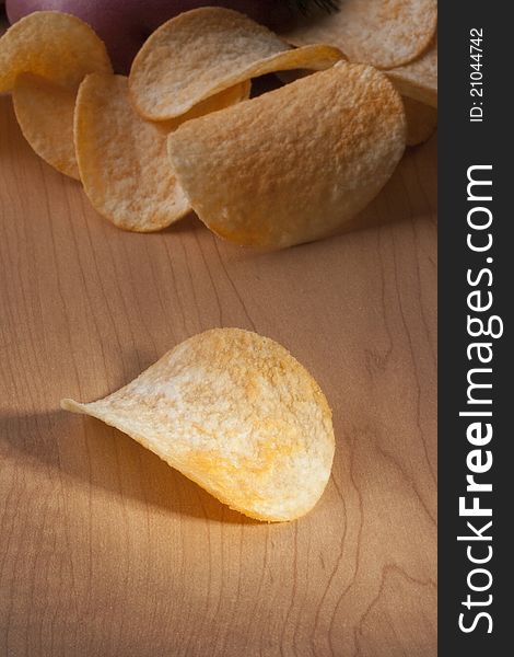 Potato chips with a potato on a kitchen board.