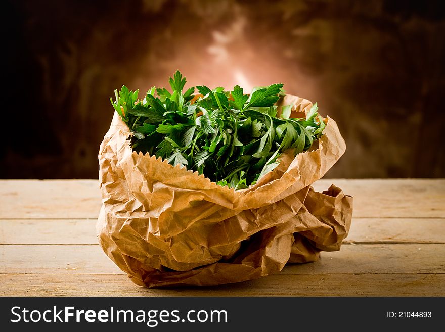 Photo of fresh parsley inside a paper bag on wooden table