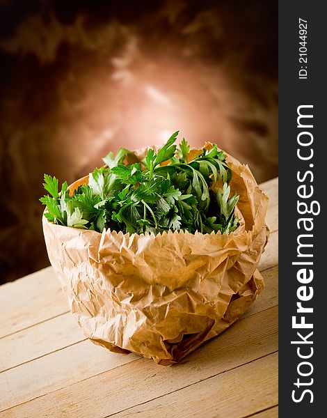 Photo of fresh parsley inside a paper bag on wooden table