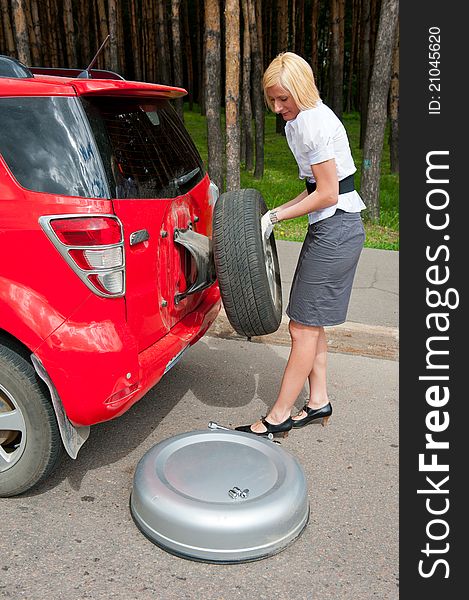 Blonde changing tire alone on a road. Blonde changing tire alone on a road