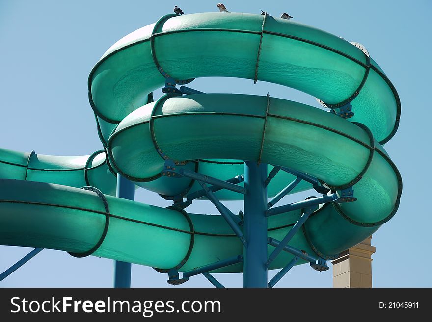 This is a view of the coiled tubes of a green water slide at a tourist amusement park