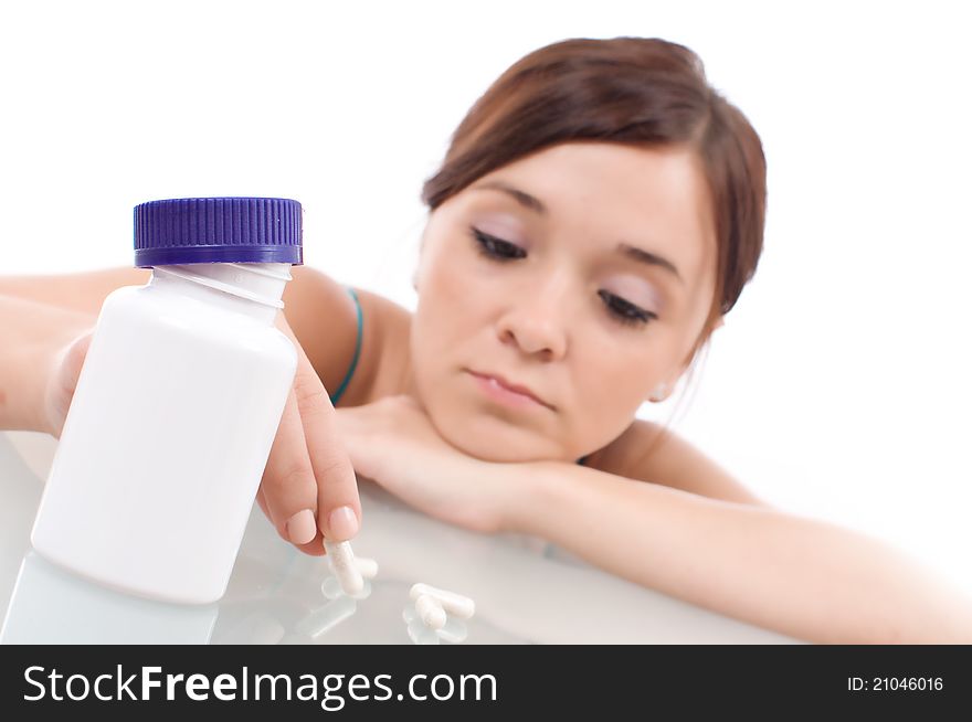 Stressed attractive young brunette with some pills, isolated on white