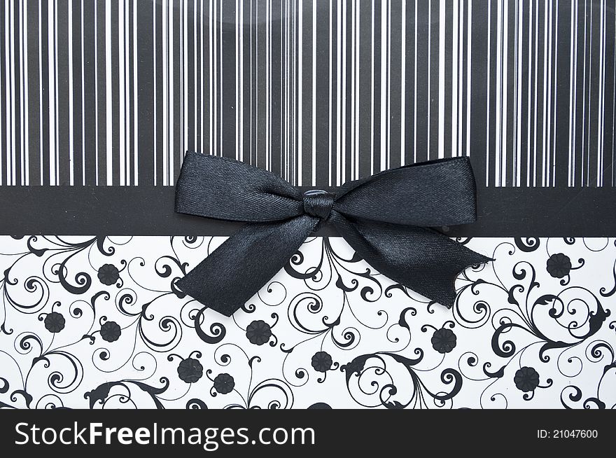 Black gift bow on black seamless pattern - background for shopping concept