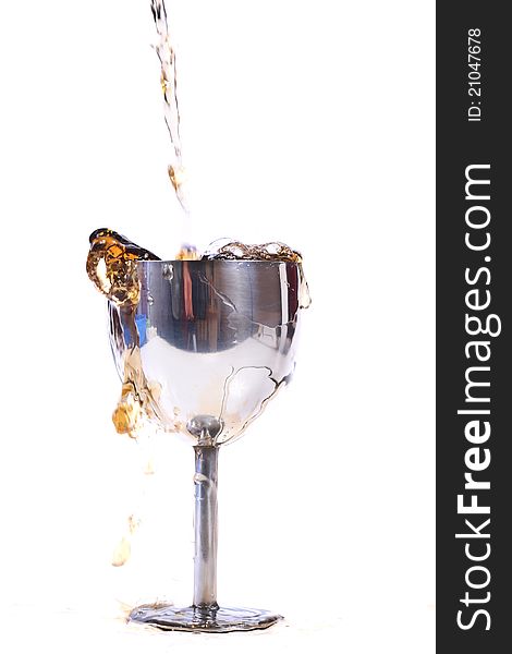 Pouring drink in metal glass isolated on white background